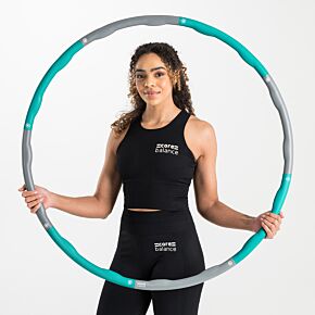 Lady sitting cross-legged on the floor, holding a teal Core Balance 1kg wavy weighted hula hoop in front of her.